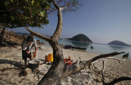 In this Sunday, Feb. 9, 2014 photo, a woman belonging to Moken tribe, nomads of the sea, cooks food in the shade of a tree on Island 115 in Mergui Archipelago, Myanmar. Isolated for decades by the country’s former military regime and piracy, the Mergui archipelago is thought by scientists to harbor some of the world’s most important marine biodiversity and looms as a lodestone for those eager to experience one of Asia’s last tourism frontiers before, as many fear, it succumbs to the ravages that have befallen many of the continent’s once pristine seascapes. (AP Photo/Altaf Qadri)