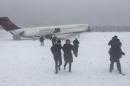 Passengers walk from a Delta jet which skidded off the runway at Laguardia airport is attended by emergency personnel in New York City