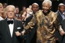 FILE- In this file photo dated Wednesday Nov. 12, 2008, George Bizos, left, arrives for his 80th birthday party with former South African president Nelson Mandela, in Johannesburg. The 85-year old legal warhorse has tousled white hair, a soft, sometimes quavering voice, describes himself as 