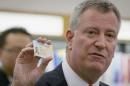 New York City mayor Bill de Blasio holds his new municipal identification card during a news conference at the Queens Library in the Queens Borough of New York