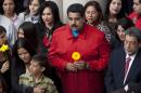 Venezuela's President Nicolas Maduro, holding a flower, and first lady Cilia Flores, second from right, gather with others at the tomb of Venezuela's late President Hugo Chavez to mark the two year anniversary of his death inside the 4F military museum in Caracas, Venezuela, Thursday, March 5, 2015. Chavez died at age 58 on March 5, 2013. (AP Photo/Ariana Cubillos)