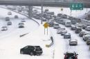 Slow moving motorists are seen on a freeway leaving downtown Charlotte as snow continues to fall in Charlotte
