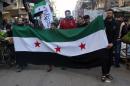 Young men hold a former Syrian flag, currently used by the rebels, during an anti government rally in the Bustan al-Qasr district of Aleppo on February 20, 2014