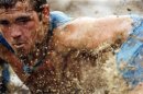 Mud flies in front of a competitor as he swims through mud underneath electrified wires during the Tough Mudder at Mt. Snow in West Dover