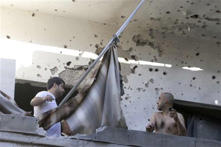 Two men inspect their damage house after two rockets hit their area in a Beirut suburbs May 26, 2013. REUTERS/Mohammed Azakir