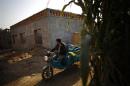 An ethnic Uighur man drives a tricycle near a construction site for new houses in Turpan, Xinjiang province