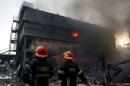 Firefighters stand at the site of a fire at a packaging factory outside Dhaka