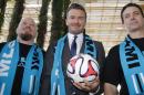 Former football star David Beckham (C), wearing a Major League Soccer scarf, posing with MLS fans at the Perez Art Museum in Miami, Florida, on February 5, 2014