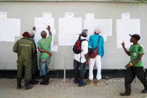 Men look for their names on lists outside a polling&nbsp;&hellip;