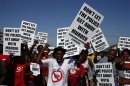 Demonstrators wave placards during a site inspection by the judicial commission of inquiry into the shootings at Lonmin's Marikana mine