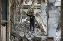A man inspects a site damaged from what activists said was shelling by forces loyal to Assad in the town of Douma