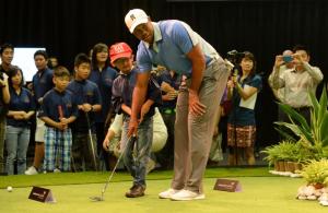 World number one golfer, Tiger Woods, helps a young …