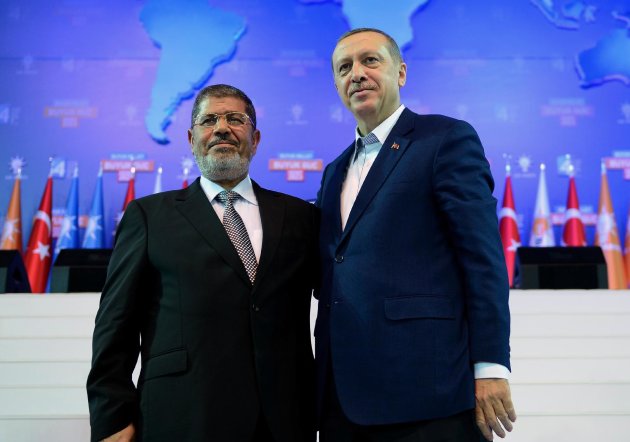 FILE -- In this Sunday, Sept. 30, 2012 file photo provided by Turkish Prime Minister's Press Service,Turkey's Prime Minister Recep Tayyip Erdogan, right, and Egyptian President Mohammed Morsi salute the members of Turkey's ruling Justice and Development Party in Ankara, Turkey. Egyptians are closely following protests in Turkey, a country that has provided the heavily polarized and increasingly impoverished Egyptians with a tantalizing model for marrying Islamist government with a secular establishment and achieving prosperity along the way. For the first time in a decade of power, Erdogan appeared vulnerable and embattled in front of tens of thousands of protesters converging every day at dozens of cities across Turkey for more than a week. (AP Photo/Kayhan Ozer, File)