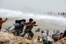 Syrian refugees run away as Turkish soldiers use water cannon to move them away from fences along the Turkish border at Akcakale on June 13, 2015