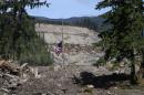 A flag honoring victims of the Oso mudslide hangs at half staff , Tuesday, April 29, 2014 in Oso, Wash. The local access road has opened through the Oso mudslide, connecting the stretch of Highway 530 blocked by the March 22 landslide. (AP Photo/The Seattle Times, Ellen M. Banner, Pool)