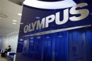 Man sits near a logo of Japan's Olympus Corp at the company headquarters in Tokyo