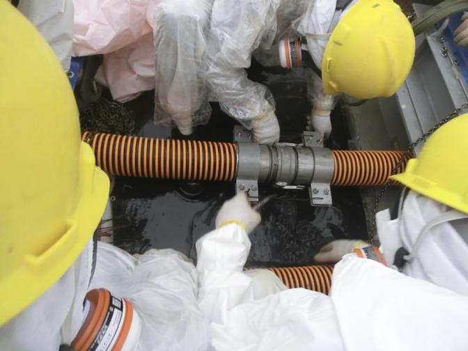 Trabalhadores vestindo roupas de proteção e máscaras são vistos de trabalho em um local onde a água radioativa vazou em (TEPCO) Fukushima Daiichi usina da Tokyo Electric Power Co nuclear em Fukushima