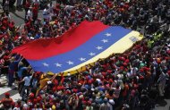 Supporters of Venezuela's late President Hugo Chavez stretch out a large national flag as they gather to see his coffin driven through the streets of Caracas, March 6, 2013. REUTERS/Jorge Dan Lopez