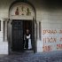 A monk stands next to graffiti sprayed on a wall at Monastery near Jerusalem
