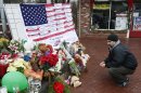 Mark Sorrentino, of Naugatuck, Conn., pays respects near a U.S. flag donning the names of victims on a makeshift memorial in the Sandy Hook village of Newtown, Conn., as the town mourns victims killed in a school shooting, Monday, Dec. 17, 2012. Authorities say a gunman killed his mother at their home and then opened fire inside the Sandy Hook Elementary School in Newtown, killing 26 people, including 20 children, before taking his own life, on Friday. (AP Photo/Julio Cortez)