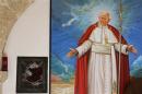 A broken glass of a niche where the reliquary with the blood of the late Pope John Paul II was located is seen next to a painting of the late Pope in the small mountain church of San Pietro della Ienca