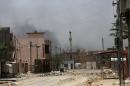 Rubble fills a street in Fallujah, Iraq, Monday, June 27, 2016. Thick clouds of black smoke billowed over the Julan neighborhood in northwest Fallujah Monday as dozens of homes continued to burn a day after the city was declared 