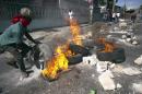 Protesters calling for the resignation of President Michel Martelly and Prime Minister Laurent Lamothe block a street with burning tires and barricades in the center of Port-au-Prince, on December 13, 2014