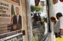 People look at the front pages of newspapers displayed behind the window of a shop in Ericeira village