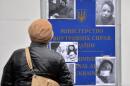 A passer-by looks at a signboard of the Ukrainian Internal Affairs Ministry in Kiev with photos of Tetyana Chornovil, popular Ukrainian journalist and opposition activist, during a picket of the opposition on December 25, 2013