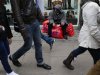 A shopper rests on his sale bags as others walk past him on Oxford Street in central London