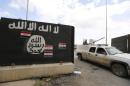 Iraqi security forces ride a vehicle past a wall painted with the black flag commonly used by Islamic State militants, near former Iraqi president Saddam Hussein's palace in Tikrit