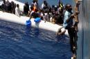 Dramatic footage emerged Tuesday May 5, 2015, filmed by a crew member, showing a Mediterranean Sea rescue of migrants on a sinking rubber boat desperately clambering up ropes and a ladder from the cargo ship Zeran that came to their aid on May 3, 2015, in the sea between Libya and Sicily. Five bodies were recovered and were brought ashore Tuesday along with the migrant survivors to the port in Catania, Sicily, Italy. (AP Photo) TV OUT - NO ARCHIVES