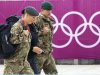 Members of the armed forces walk past the Olympic rings on the perimeter of the Olympic Park in Stratford, east London