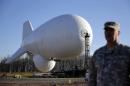 U.S. Air Force Col. William Pitts stands in front of an unmanned aerostat that is part of a new U.S. military cruise-missile defense system during a media preview, Wednesday, Dec. 17, 2014, in Middle River, Md. Military officials said a pair of helium-filled aerostats stationed in Maryland are intended provide early detection of cruise missiles over a large swath of the East Coast, from Norfolk, Va., to upstate New York, during a three-year test. JLENS, short for Joint Land Attack Cruise Missile Defense Elevated Netted Sensor System, will be fully implemented this winter. (AP Photo/Patrick Semansky)