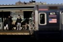 Commuters watch as a train enters the 40th St-Lowry St Station, where a man was killed after being pushed onto the subway tracks, in the Queens section of New York, Friday, Dec. 28, 2012. Police are searching for a woman suspected of pushing the man and released surveillance video Friday of her running away from the station.(AP Photo/Seth Wenig)