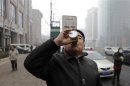Chinese multimillionaire Chen Guangbiao demonstrates how to use his canned fresh air during an interview with Reuters near a busy street on a hazy day in central Beijing