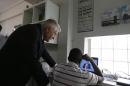 Council of Europe Secretary General Thorbjorn Jagland, left, stands next to a migrant boy as they watch a French channel on a laptop at a facility housing unaccompanied children in Athens, Thursday, May 26, 2016. Jagland, one of Europe's top human rights officials, says it is "unacceptable" that any refugee and migrant children who arrive on the continent unaccompanied by their parents are held in detention centers, and called on European countries to ensure such children can be housed in special facilities and quickly reunited with their families. (AP Photo/Thanassis Stavrakis)