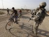 A resident rides a bicycle past U.S. Army soldiers on the outskirts of Kut