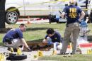 FBI investigators collect evidence, including a rifle, where two gunmen were shot dead after their bodies were removed in Garland