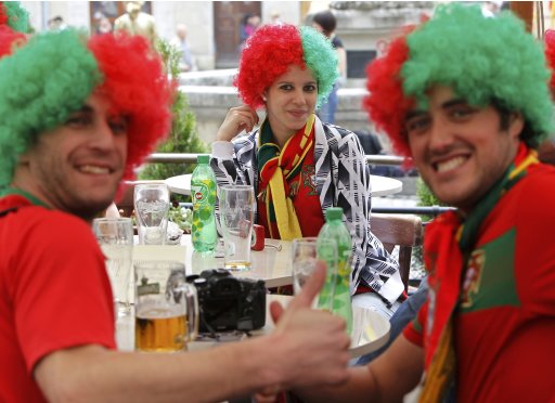 Portuguese soccer fans pose for a photograph as they drink beer in central Lviv