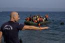 A Greek police man gives instuction as migrants whose boat stalled at sea while crossing from Turkey to Greece approach a shore of the island of Lesbos, Greece, on Sunday, Sept. 20, 2015. A boat with 46 migrants or refugees has sunk Sunday in Greece and the coast guard says it is searching for 26 missing off the eastern Aegean island of Lesbos. (AP Photo/Petros Giannakouris)