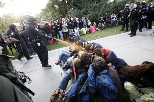 In this Friday, Nov. 18, 2011, photo University of California, Davis Police Lt. John Pike uses pepper spray to move Occupy UC Davis protesters while blocking their exit from the school&#39;s quad Frid