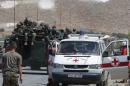 Lebanese soldiers drive armoured vehicles past emergency personnel at the entrance of the town of Arsal, on August 4, 2014