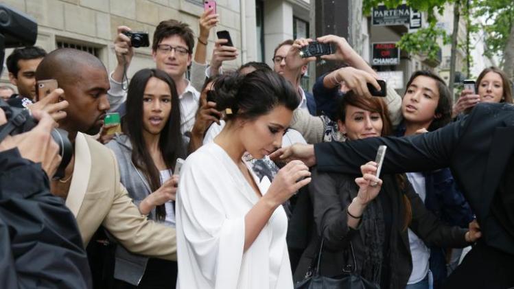 People gather around American reality TV star Kim Kardashian (C) and American singer Kanye West (L) and they leave their residence in Paris on May 23, 2014, ahead of their wedding