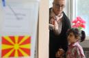 A woman with a child goes to a polling box to cast her ballot, at a polling station in Skopje, Macedonia, on Sunday, April 27, 2014. Macedonia votes Sunday on presidential runoff election and snap parliamentary elections. (AP Photo/Boris Grdanoski)