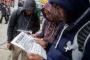 Mott Hall High School student Brian Binion, right, and fellow students read fliers about Ebola risk, near the apartment building of Ebola patient Dr. Craig Spencer, in New York, Friday, Oct. 24, 2014. Since there's no specific treatment, care is focused on easing symptoms to give the body enough time to fight off an infection, (AP Photo/Richard Drew)