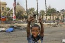An Egyptian child displays empty tear gas canisters among the debris of a protest camp in Nahda Square, near Cairo University in Giza, Cairo, Egypt, Thursday, Aug. 15, 2013. Egypt faced a new phase of uncertainty on Thursday after the bloodiest day since its Arab Spring began, with over 300 people reported killed and thousands injured as police smashed two protest camps of supporters of the deposed Islamist president. Wednesday's raids touched off day-long street violence that prompted the military-backed interim leaders to impose a state of emergency and curfew, and drew widespread condemnation from the Muslim world and the West, including the United States. (AP Photo/Amr Nabil)