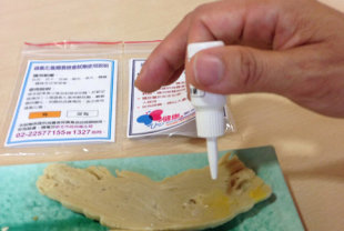 衛生局檢驗員用過氧化氫檢驗試劑檢驗豆干是否有含量過高問題。（圖片提供／新北市衛生局）