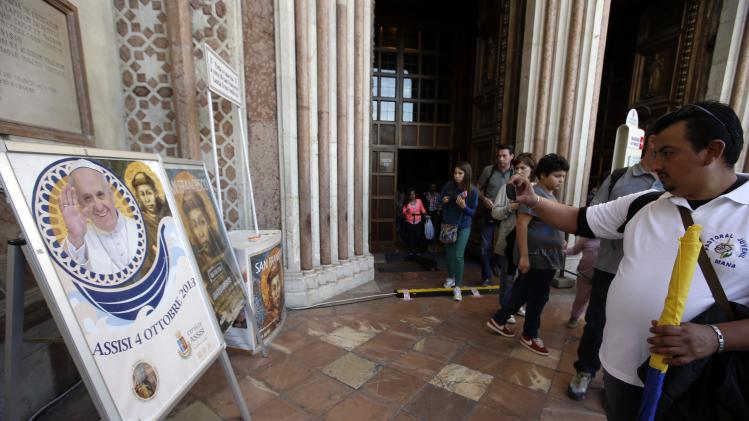 Tourists and pilgrims take pictures of a poster announcing Pope Francis' visit outside the St. Francis Basilica, in Assisi, Italy, Thursday, Oct. 3, 2013. The pontiff is scheduled to visit Assisi, the birthplace of the Italian saint who inspired his name on Friday. (AP Photo/Gregorio Borgia)