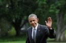 President Barack Obama waves as he walks under a rain on the South Lawn of the White House upon his return to Washington